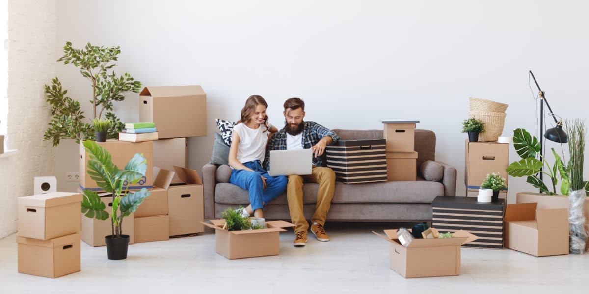 happy couple in their new apartment flanked by boxes of their belongings