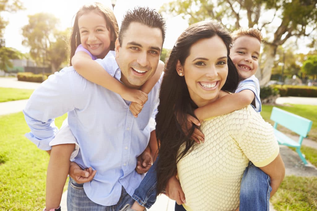 a happy hispanic family smiling outside of their apartments for rent 