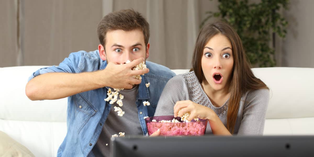 young couple watching television and eating popcorn