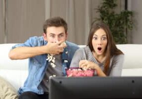 young couple watching television and eating popcorn